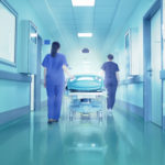Corridoio d'ospedale con barella e luci e due infermiere