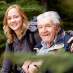 Uomo anziano con demenza senile assieme a sua figlia che lo assiste, sorridono nella foto